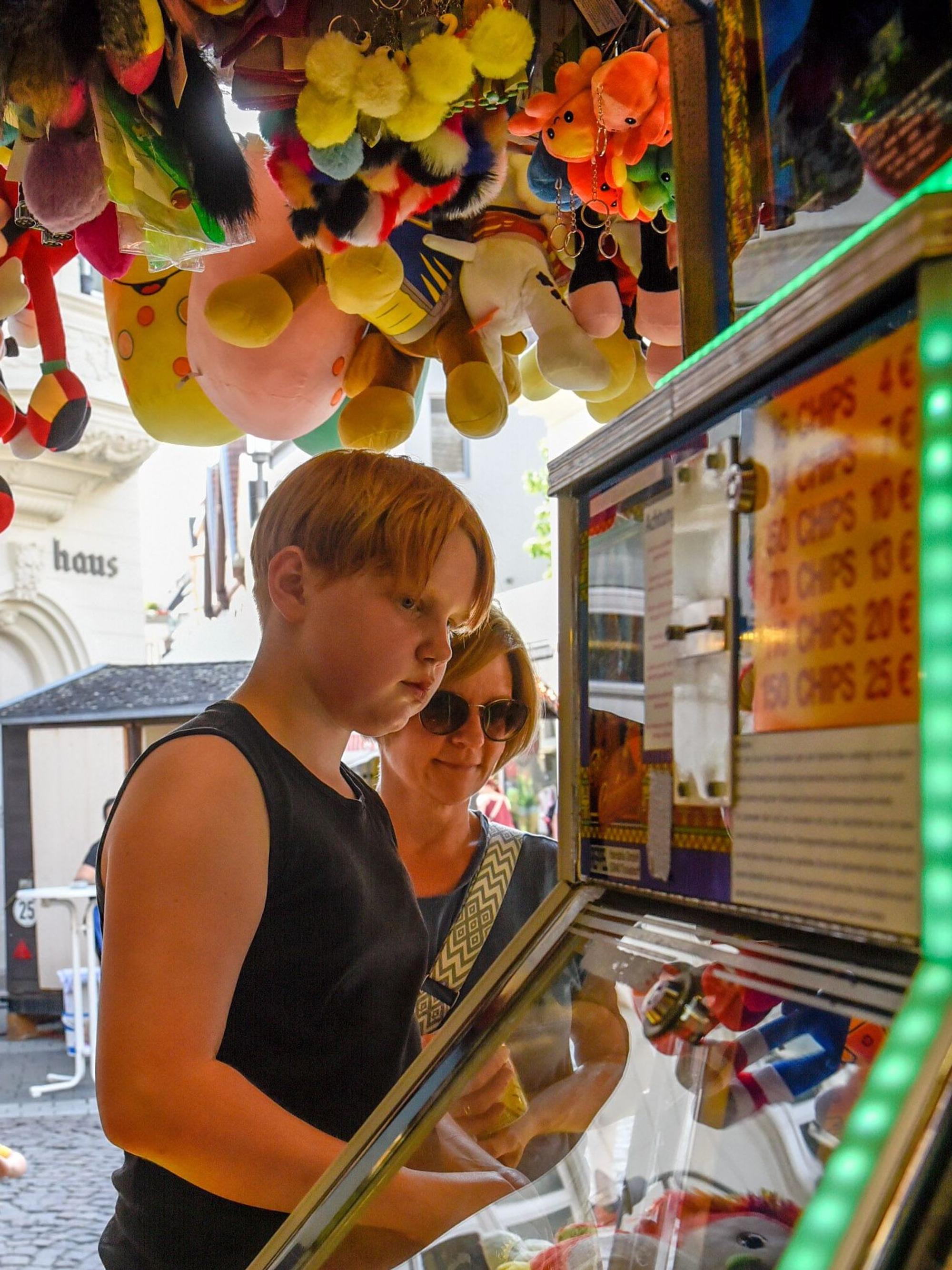 Das Bild zeigt einen Jungen an einem Spielautomaten auf der Kirmes.