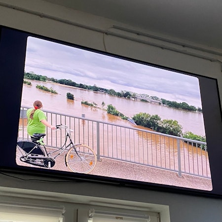 Auf einer Leinwand ist ein Filmausschnitt zu sehen, Wasser, so weit das Auge reicht.