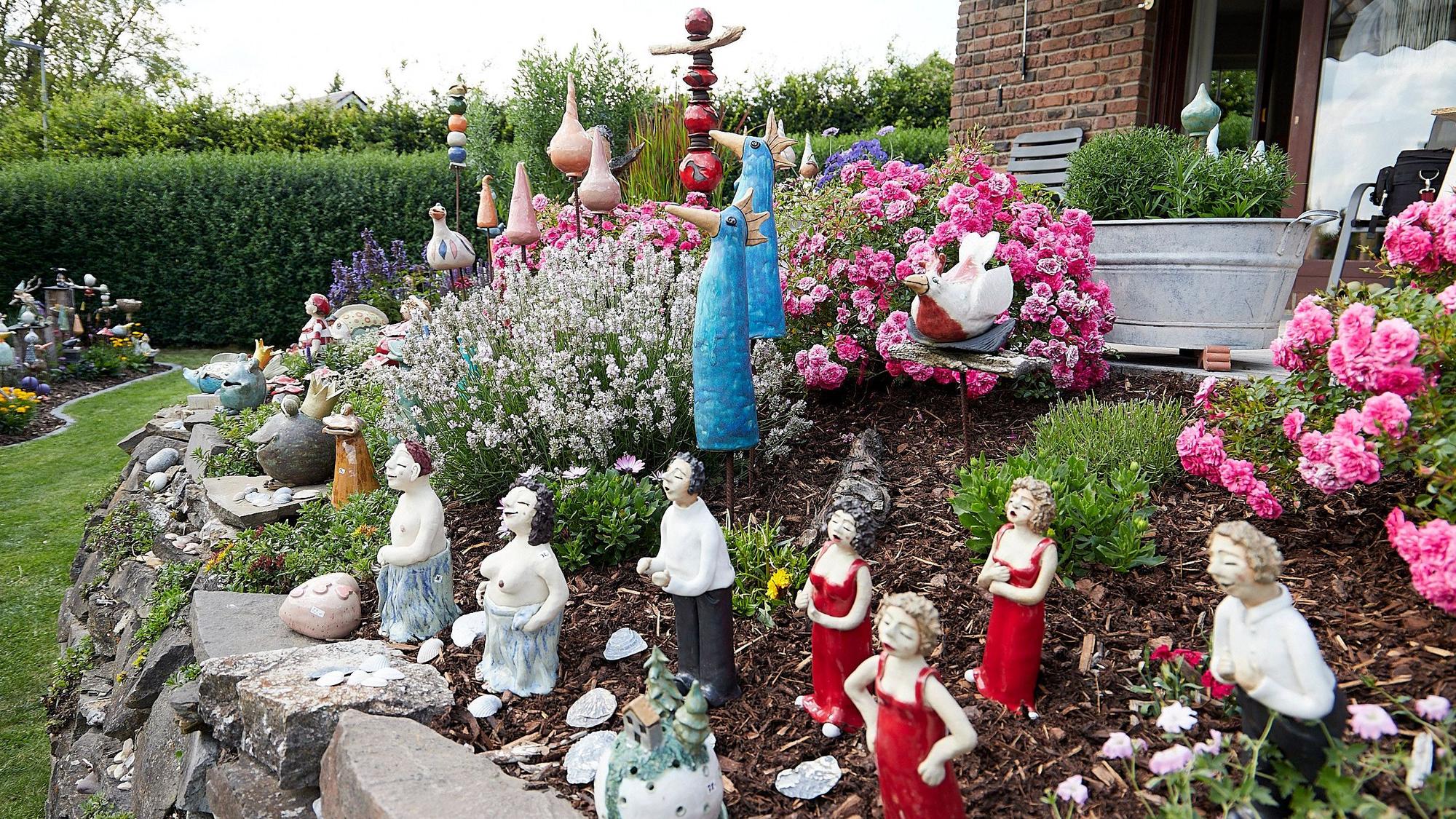 Zahlreiche Figuren aus Keramik bevölkern einen Hang im Garten.