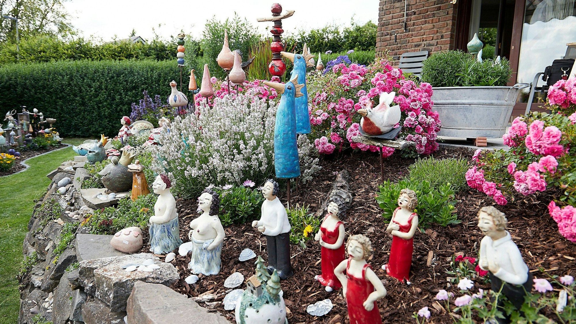 Zahlreiche Figuren aus Keramik bevölkern einen Hang im Garten.