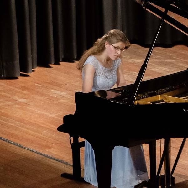 Amelie Westkamp spielt auf einer Bühne auf einem Flügel.