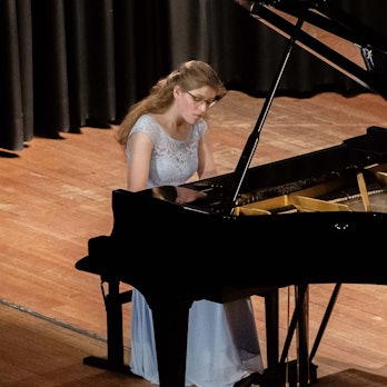 Amelie Westkamp spielt auf einer Bühne auf einem Flügel.