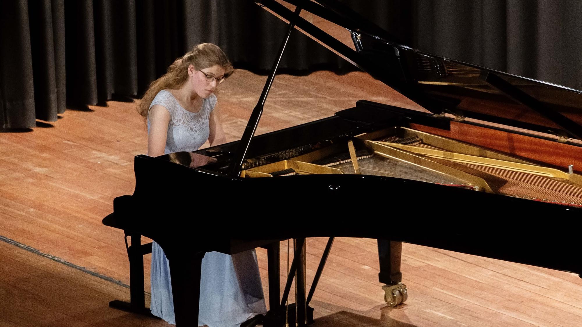Amelie Westkamp spielt auf einer Bühne auf einem Flügel.