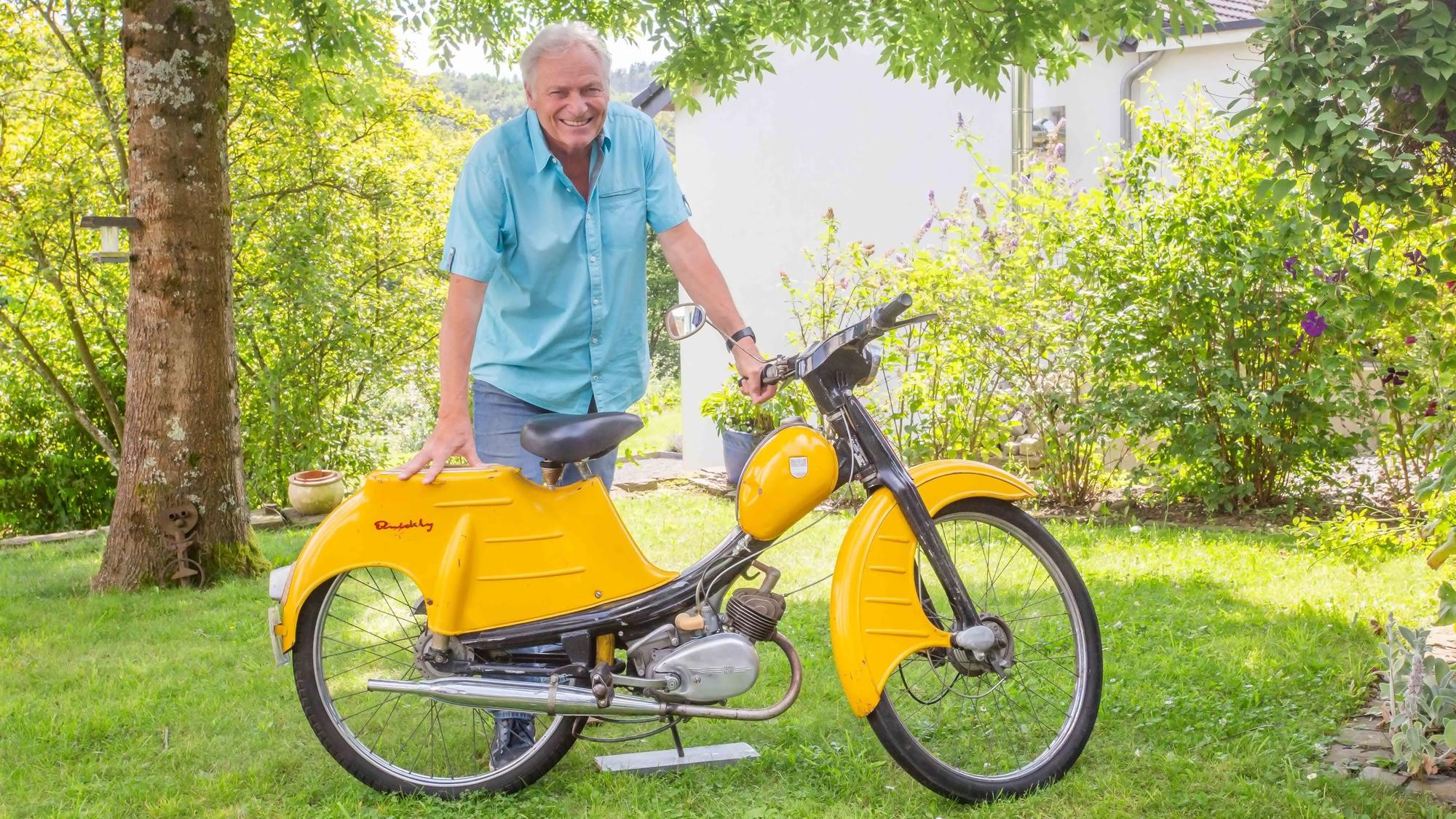 Ein Mann lehnt auf einem Moped.