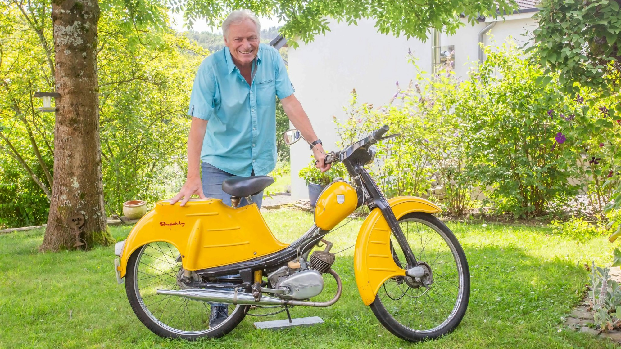 Ein Mann lehnt auf einem Moped.