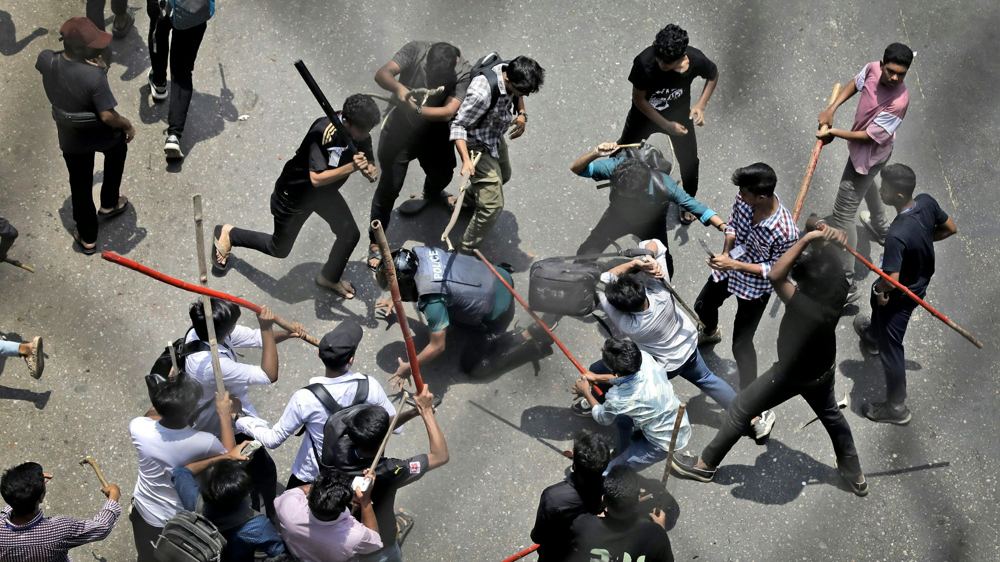 Studenten schlagen einen Polizisten mit Stöcken während eines Protestes gegen das Quotensystem im öffentlichen Dienst.