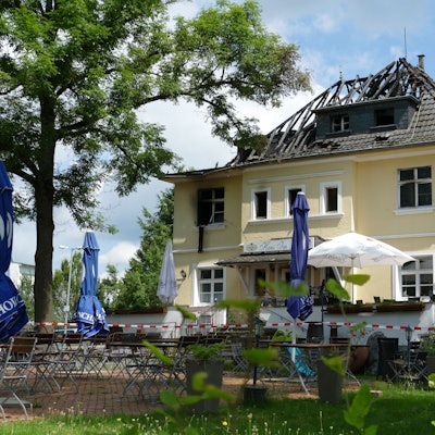 Ein Feuerwehrmann in einem Drehleiterkorb vor einem brennenden Dachstuhl.