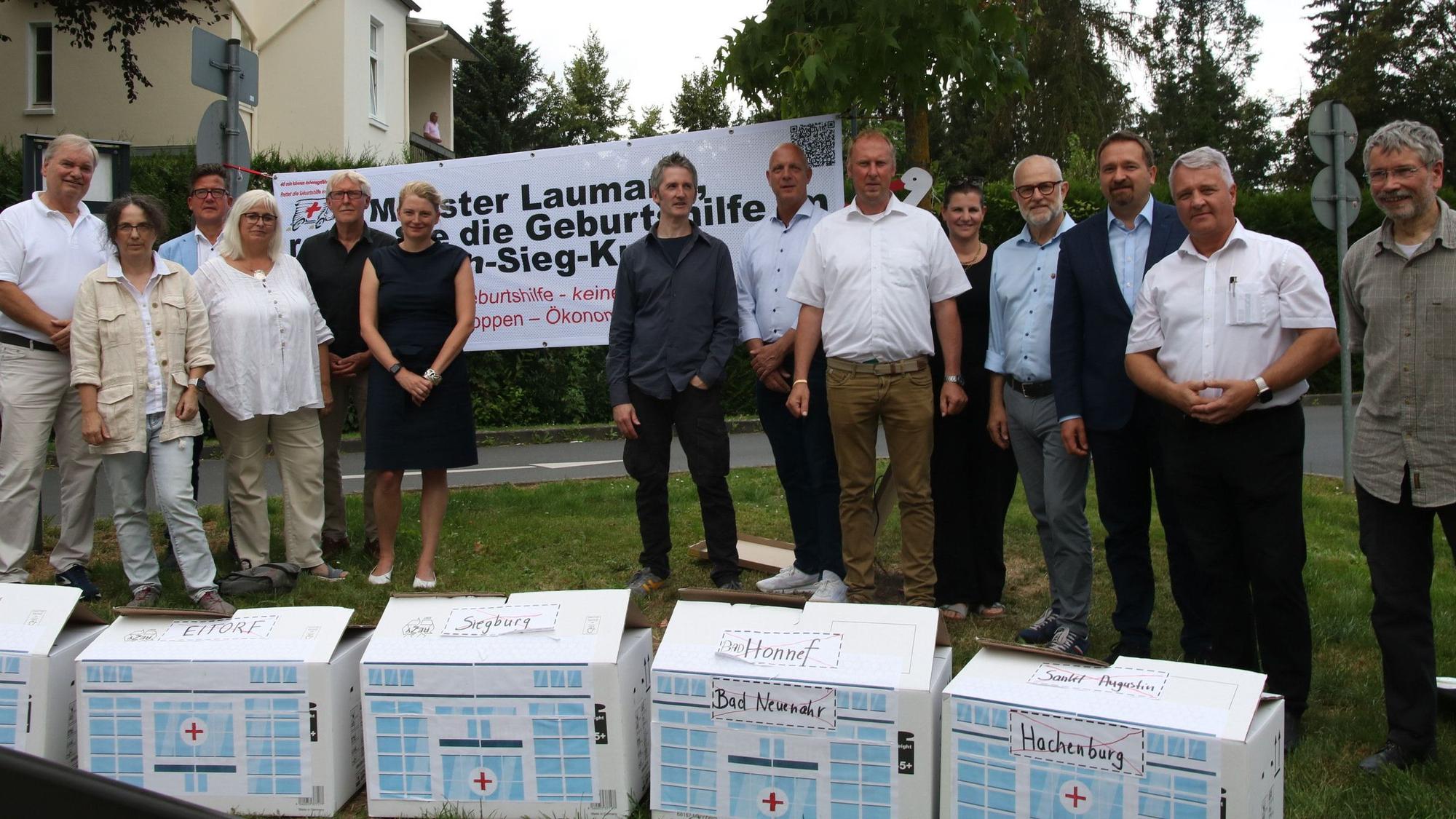 Eine Gruppe von Männern und Frauen vor einem Transparent mit der Aufschrift „Minister Laumann, retten Sie die Geburtshilfe im Rhein-Sieg-Kreis“