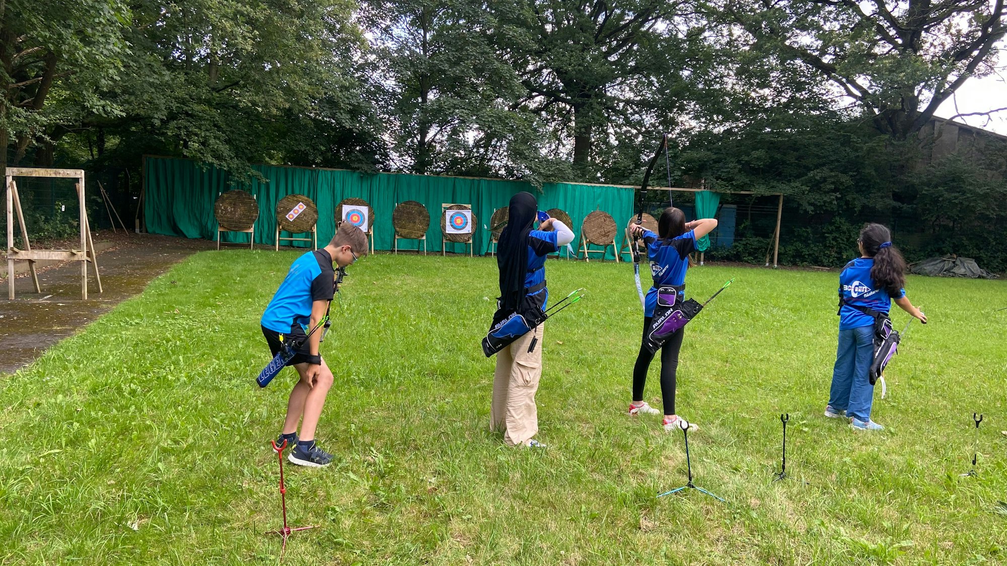 Kinder stehen in einer Reihe und schießt mit Pfeil und Bogen.