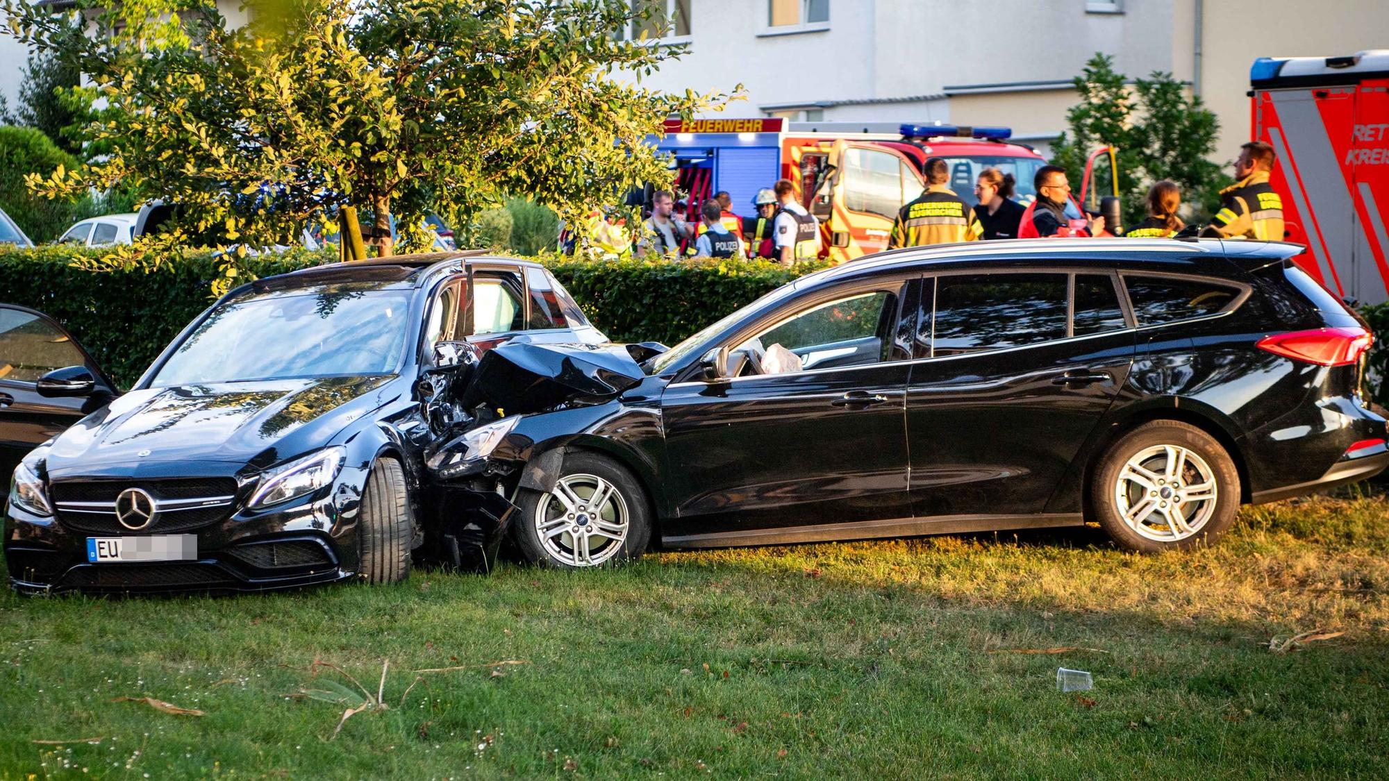Ein schwarzes Auto ist in ein anderes schwarzes Auto gefahren. Beide Wagen stehen auf einer Wiese.