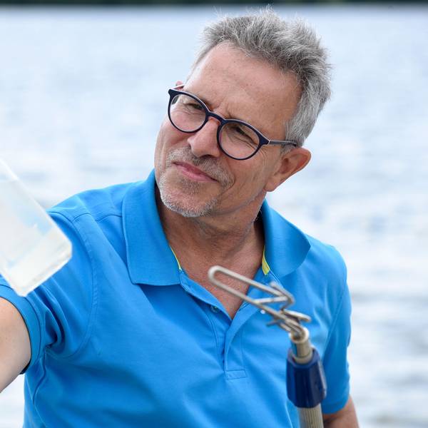 Ein Mann an einem See hält eine Flasche in der Hand.