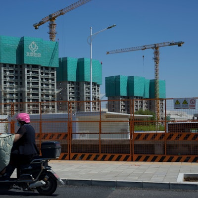 Eine Frau fährt an einem im Bau befindlichen Wohnprojekt am Stadtrand von Peking vorbei.