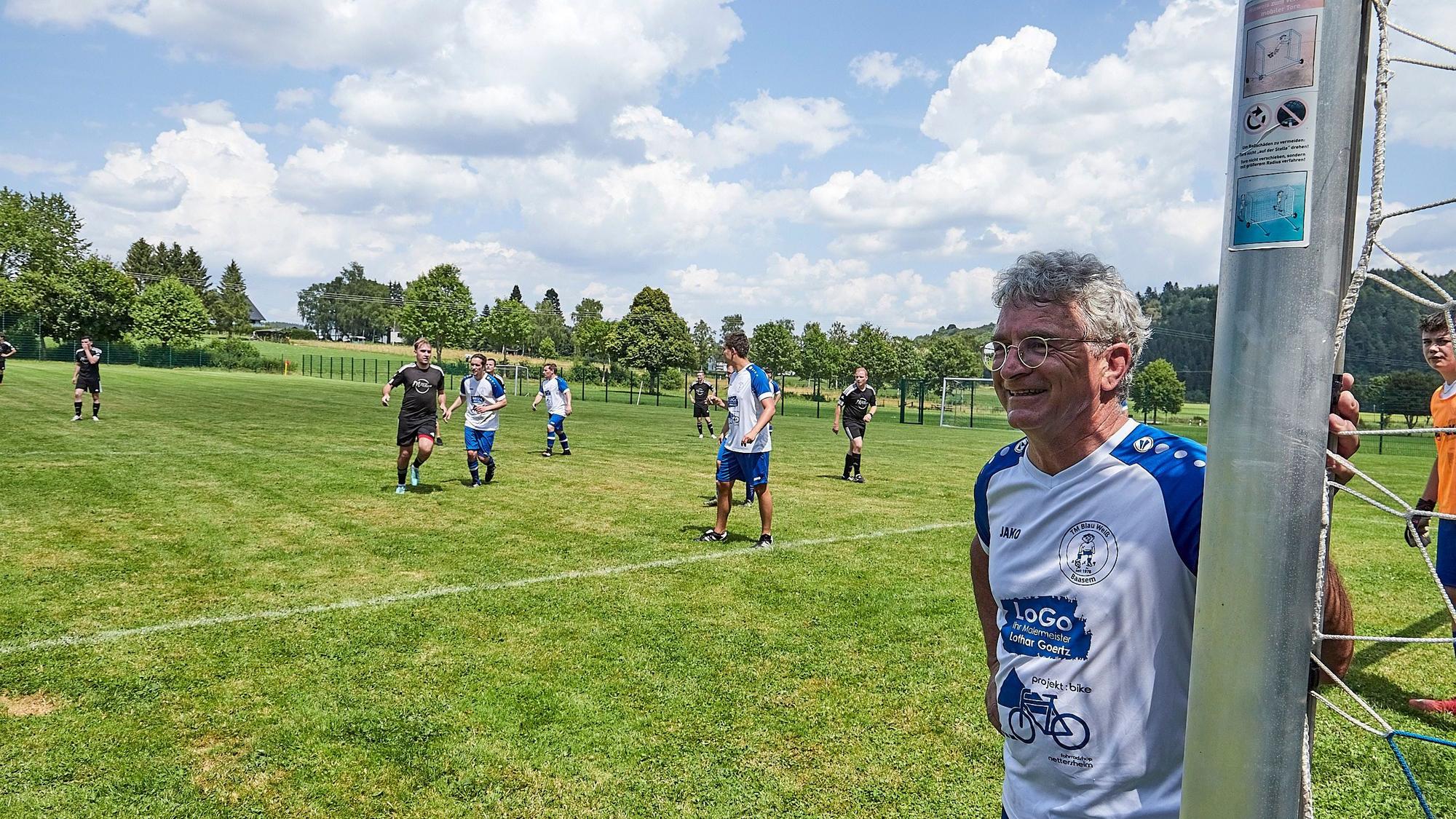 Egon Schmitz steht am Torpfosten, im Hintergrund Mitspieler und Spieler der gegnerischen Mannschaft.