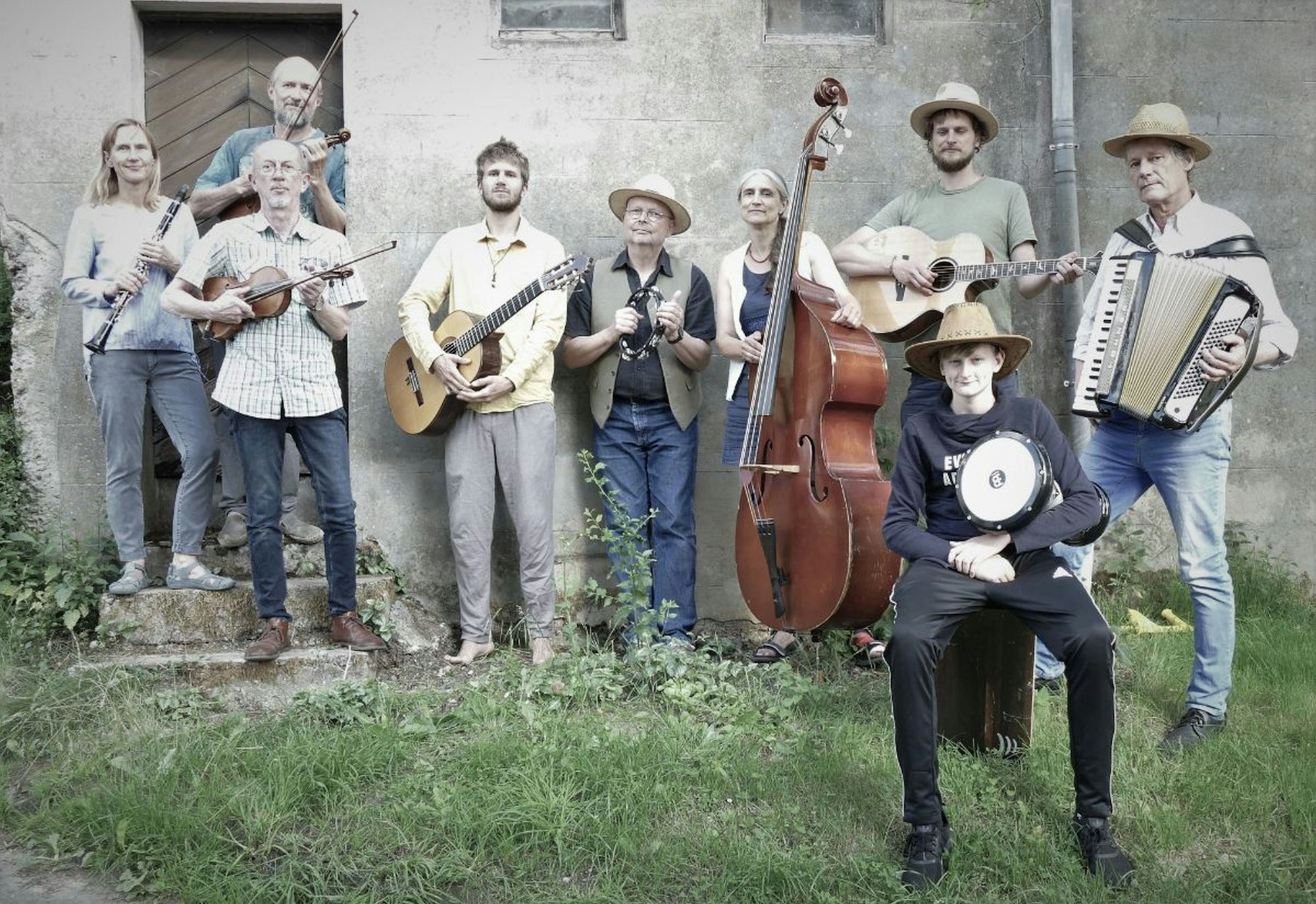 Neun Männer und Frauen mit verschiedenen Musikinstrumenten