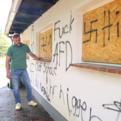 Der Waldbröler Unternehmer Michael Kappenstein steht an der beschmierten Wand seines Firmengebäudes an der Talstraße. Inzwischen gibt es offenbar ein Foto, das die Täter bei der Flucht zeigen könnte.