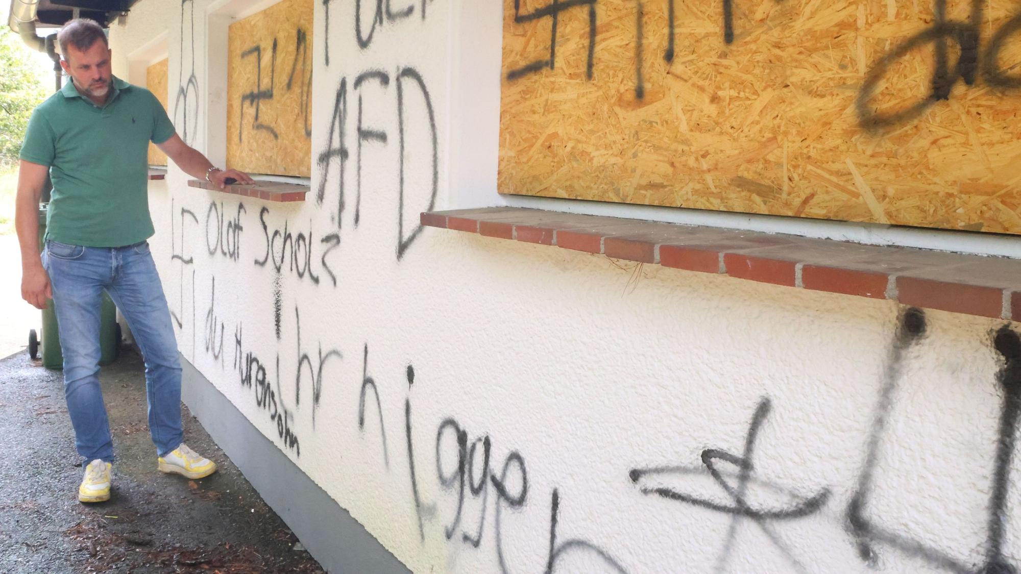 Der Waldbröler Unternehmer Michael Kappenstein steht an der beschmierten Wand seines Firmengebäudes an der Talstraße. Ein Anwohner hat ihm ein Foto zur Verfügung gestellt, das zwei Jugendliche beim Weglaufen zeigt.