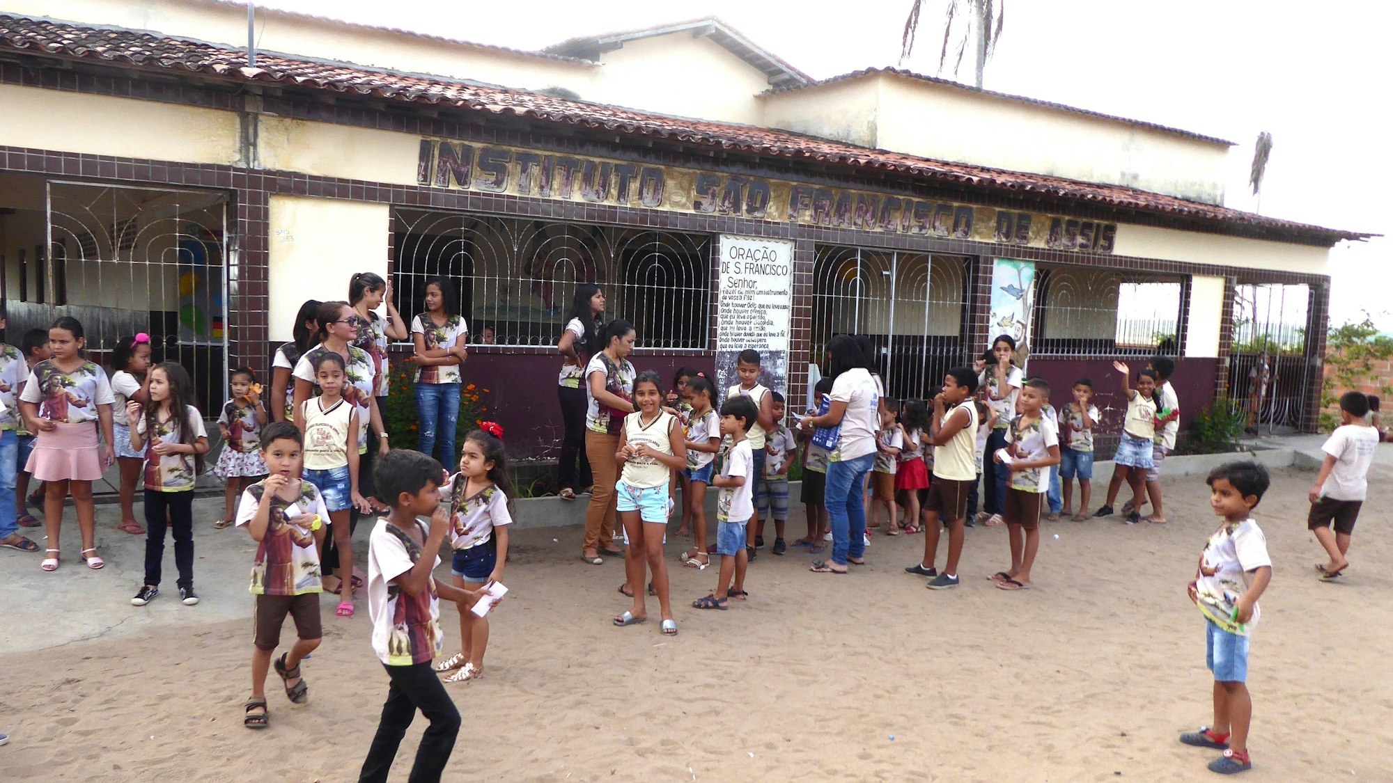Blick auf das Schulgebäude, vor dem Kinder und Jugendliche stehen.