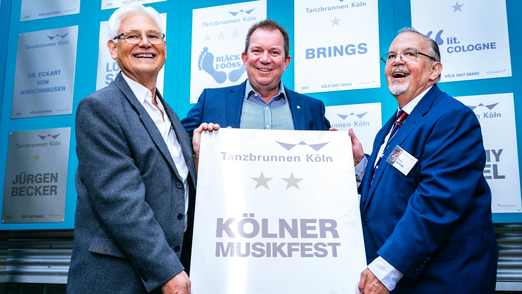 Winfried Haushalter und Klaus Schulz halten fröhlich die Ehrentafel in die Kamera. Hinter der Tafel steht Ralf Nüsser mit einem Lächeln im Gesicht.