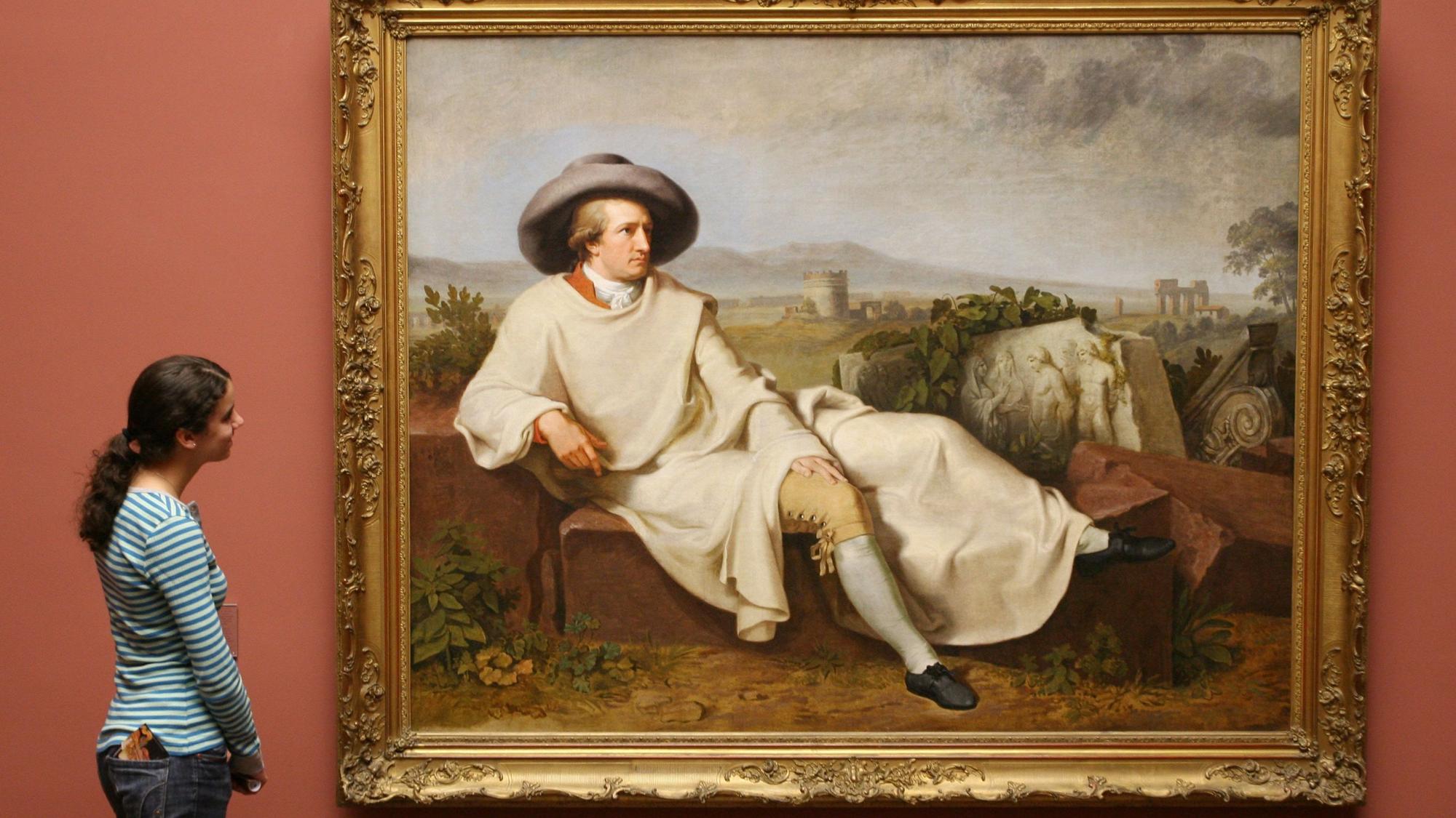 Eine Frau steht vor einem Bildnis von Goethe.