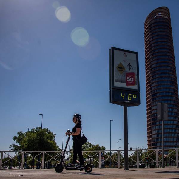 Eine Frau fährt auf einem E-Roller, im Hintergrund zeigt ein Thermometer 46 Grad an.