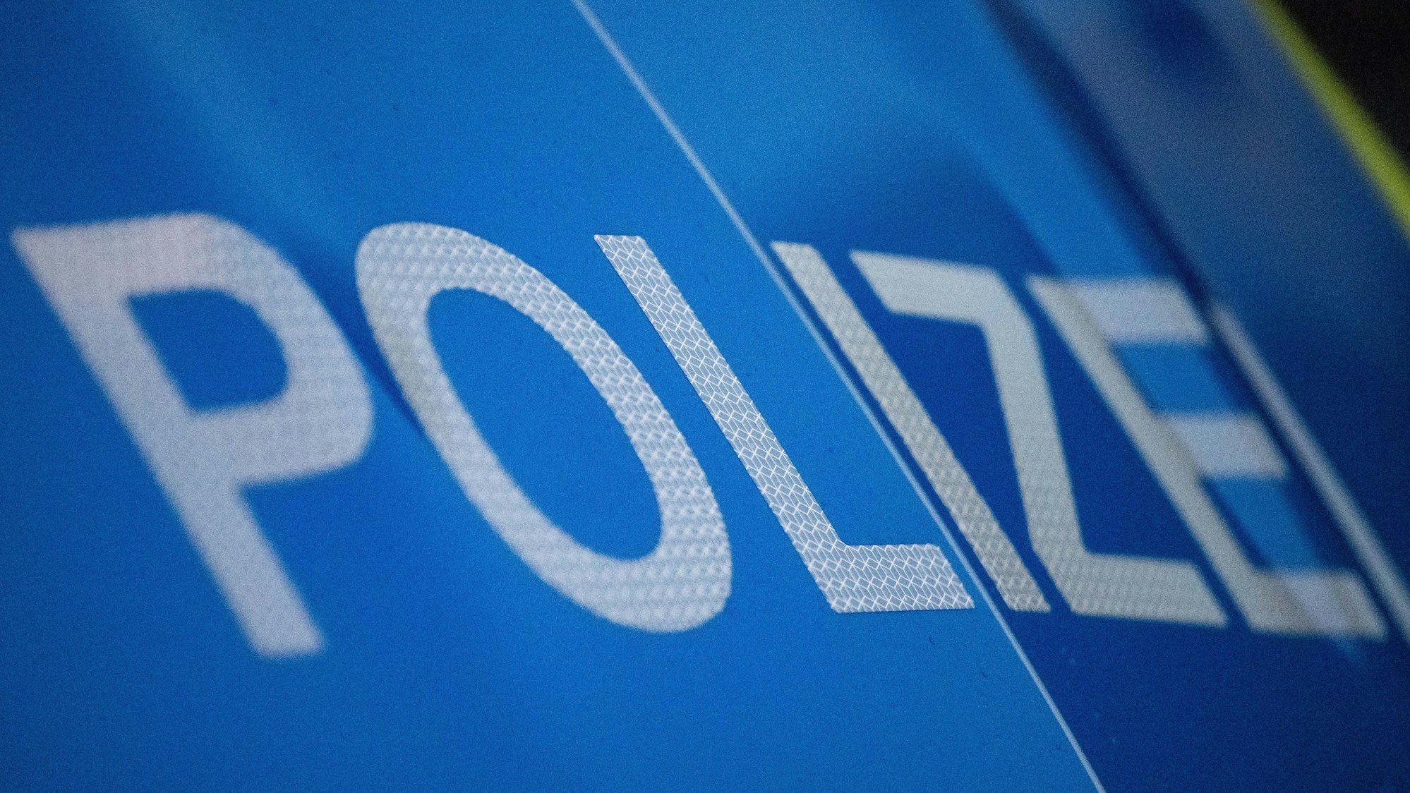 Das Bild zeigt den Schriftzug Polizei auf einem Polizeiwagen.