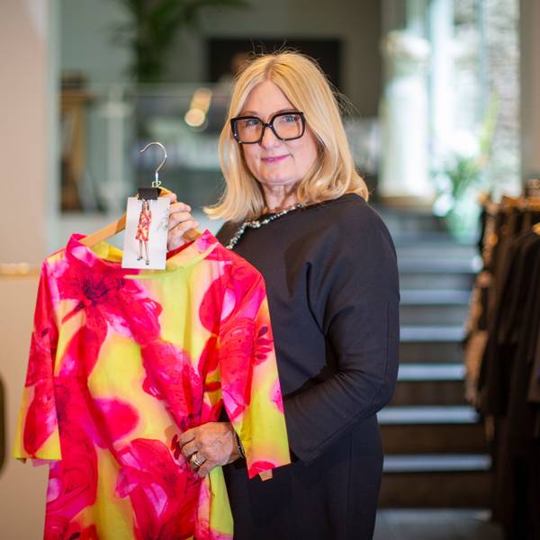 Gabriele Koch hält ein Kleid in Pink und Gelb.