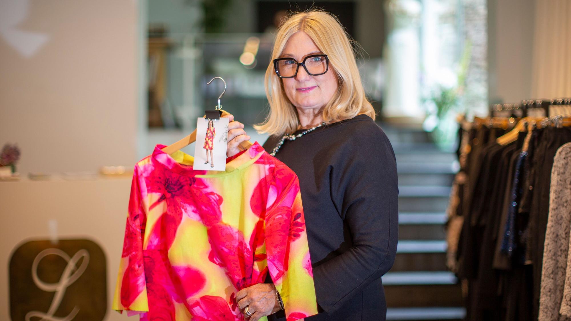 Gabriele Koch hält ein Kleid in Pink und Gelb.