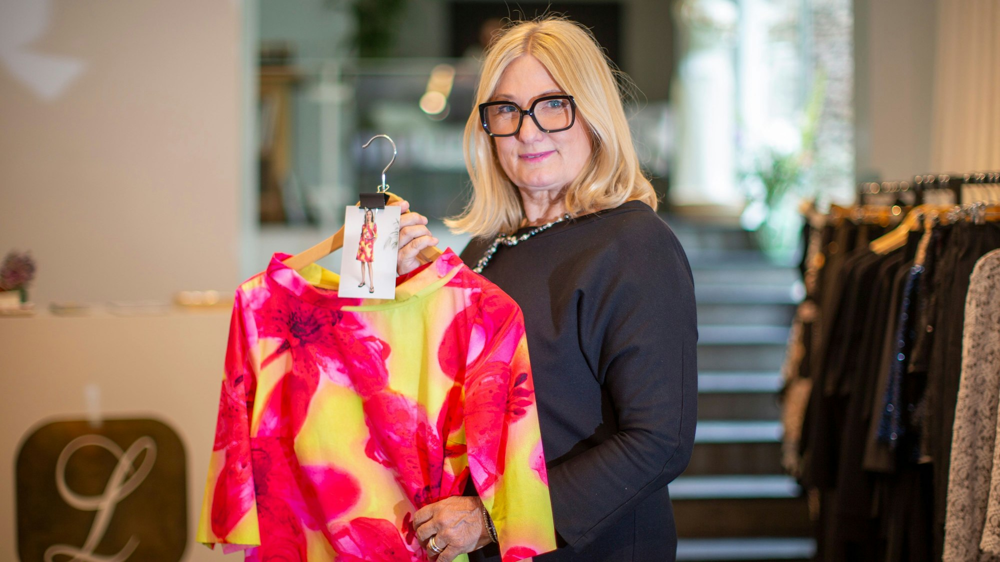 Gabriele Koch hält ein Kleid in Pink und Gelb.