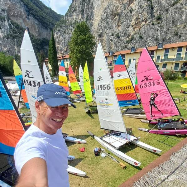 André Hauschke strahlt über das ganze Gesicht. Im Hintergrund zahlreiche Segelboote auf einer Wiese.