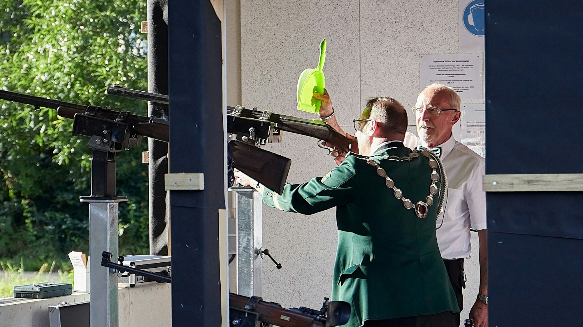 Rainer Schmitz nutzt eine Kehrschaufel, um Markus Müller vor den Strahlen der tiefstehenden Sonne zu schützen.