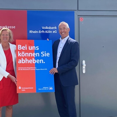 Ein Mann und eine Frau halten ein Plakat.