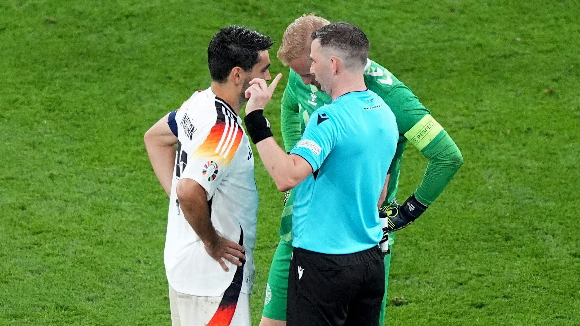 ARCHIV - 29.06.2024, Nordrhein-Westfalen, Dortmund: Fußball: EM, Deutschland - Dänemark, Finalrunde, Achtelfinale, Stadion Dortmund, Schiedsrichter Michael Oliver aus England spricht mit den beiden Kapitänen Ilkay Gündogan (l) und Dänemarks Kasper Schmeichel. (zu dpa: «Schiri-Chef fordert einheitliche Anwendung der Kapitänsregel») Foto: Marcus Brandt/dpa +++ dpa-Bildfunk +++