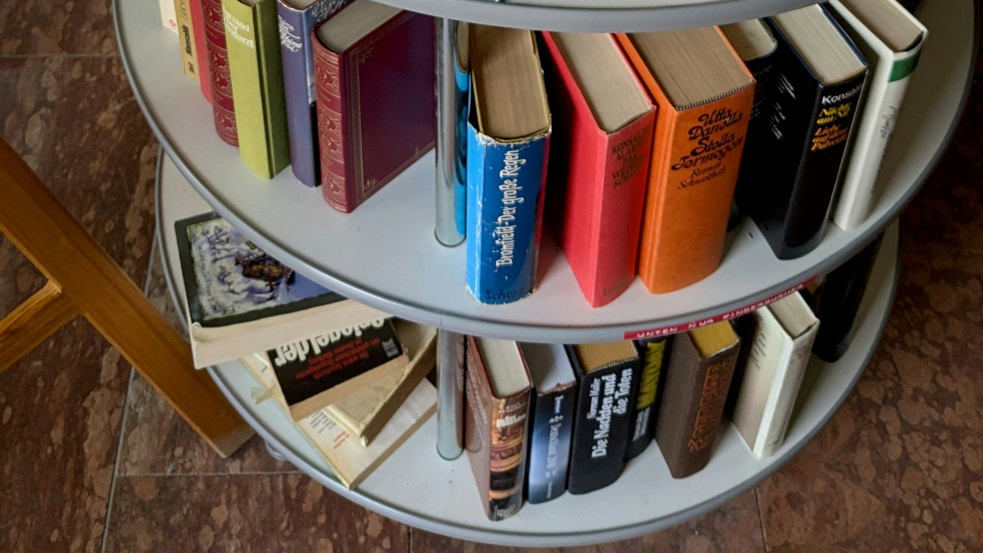 Gebundene Bücher älteren Datums stehen auf mehreren Etagen eines runden Regals.