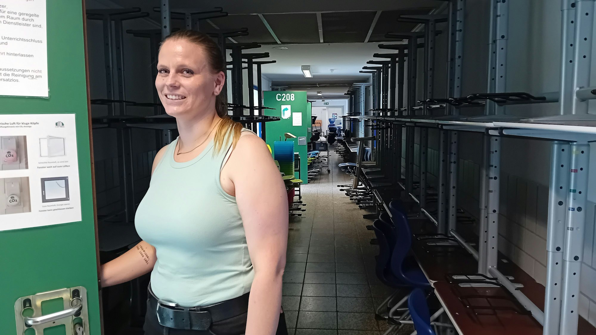 Eine Frau öffnet die Tür zu einem Klassenzimmer.