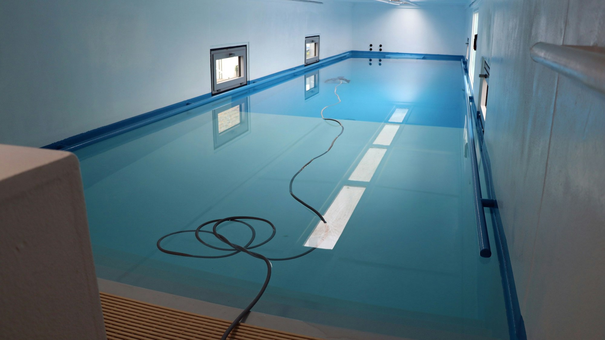 Das Bild zeigt einen Schwimmcontainer von innen. Auf dem Wasser treibt ein Wasserschlauch.