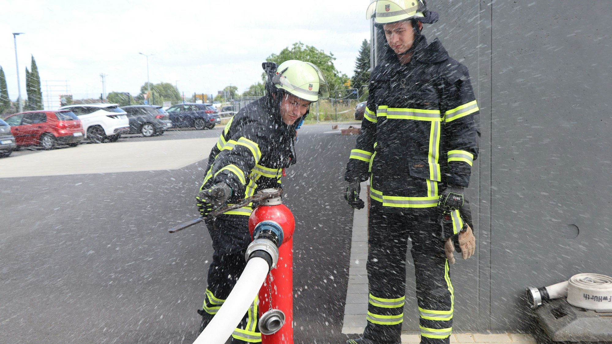Zwei Feuerwehrmänner arbeiten an einem Hydranten.