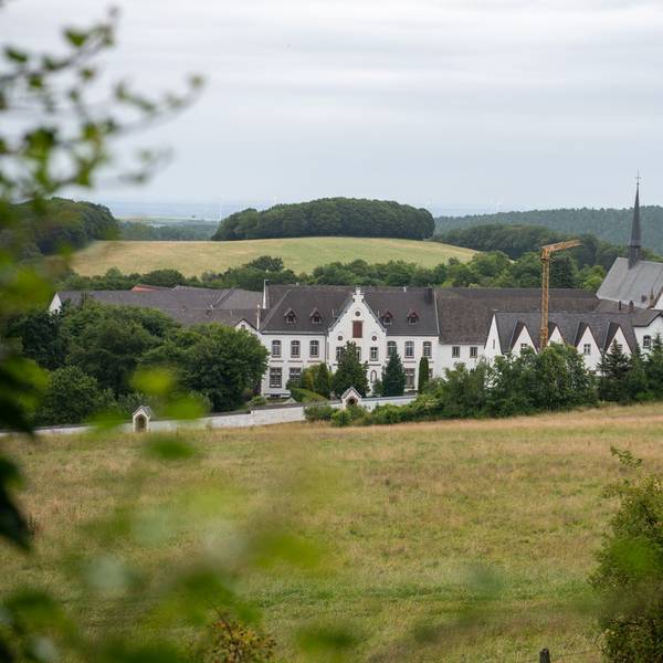 Blick auf das Kloster Mariawald, ringsumher sind Hügel und Wald zu sehen.