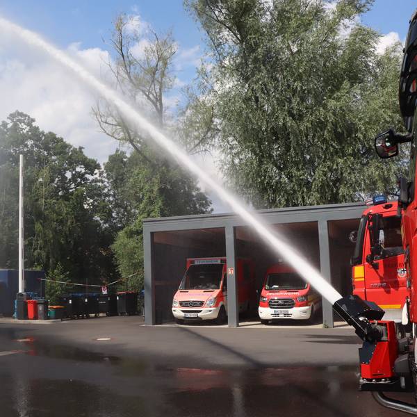 Zu sehen ist Löschwasser, das im hohen Bogen aus einem Schlauch kommt.