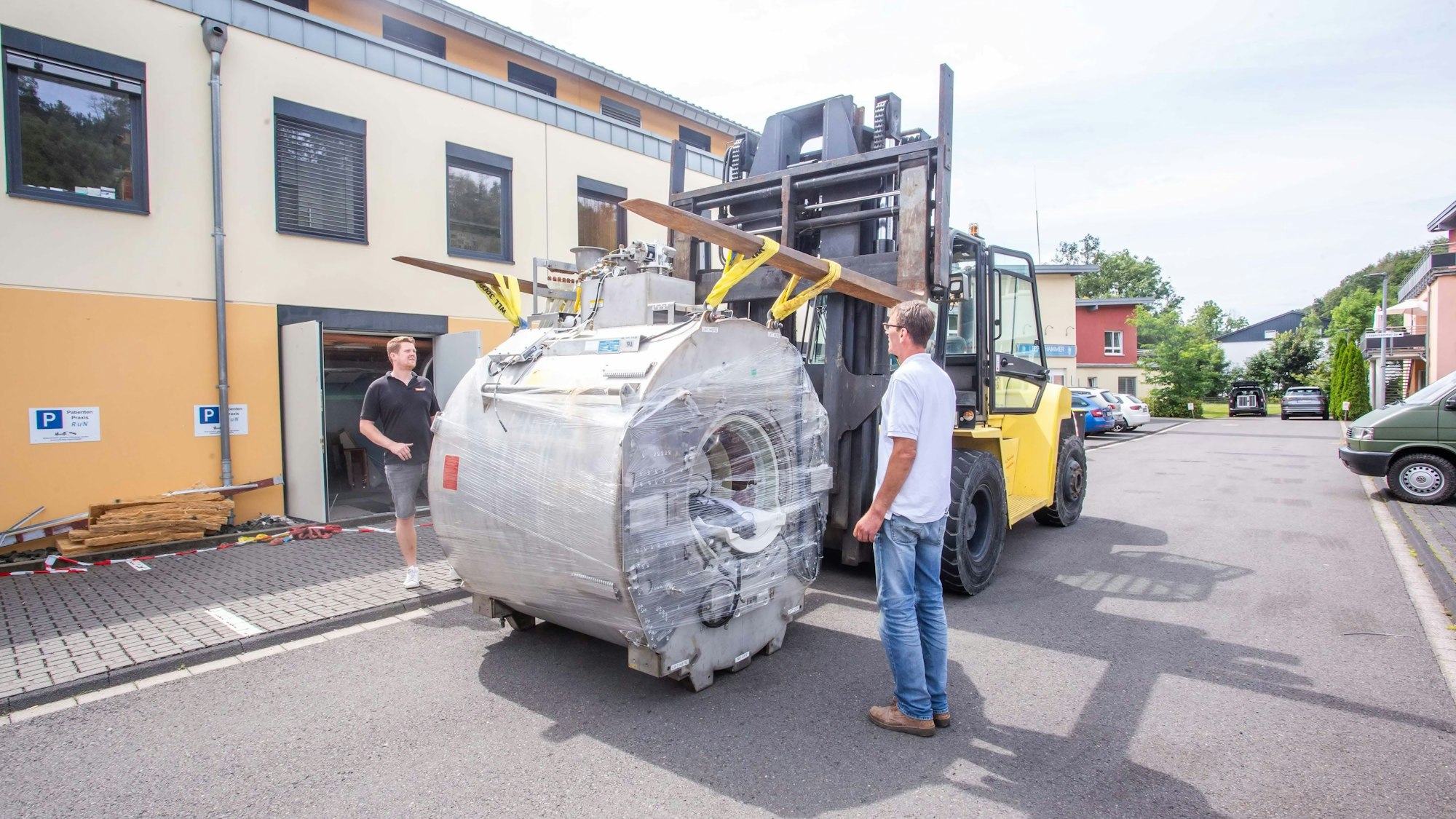 Zwei Männer stehen neben einer großen Spule, die an an die Gabeln eines Gabelstaplers gehängt ist.