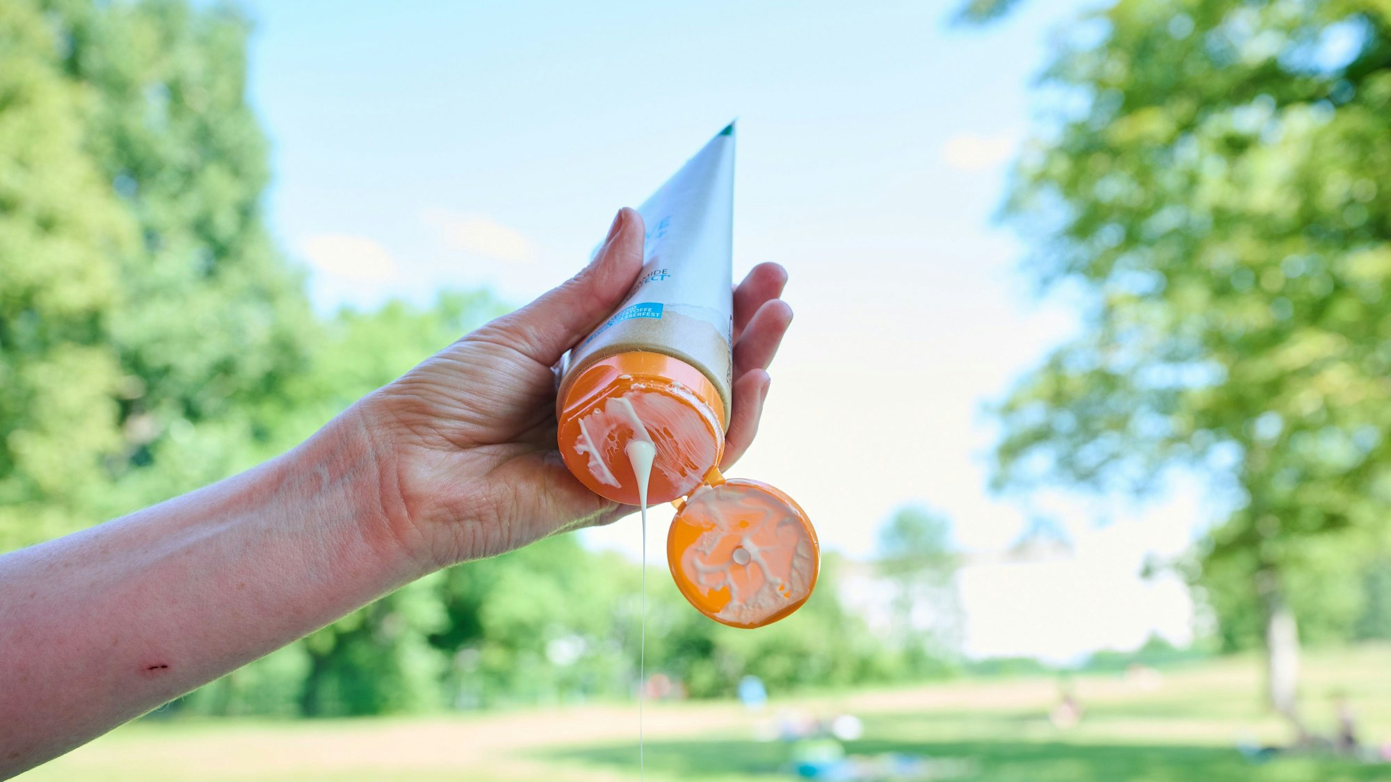 Eine Frau nimmt sich Sonnenmilch aus der Tube.