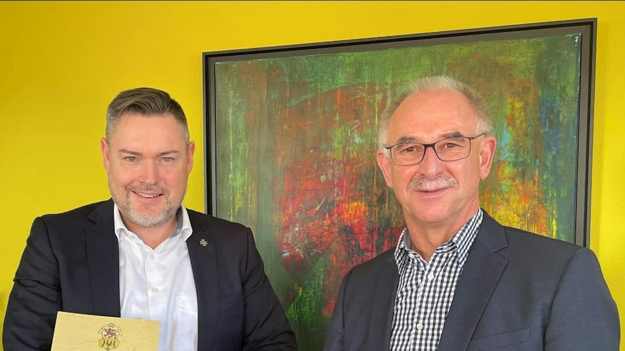 Zwei Männer vor einer gelben Wand und einem Gemälde