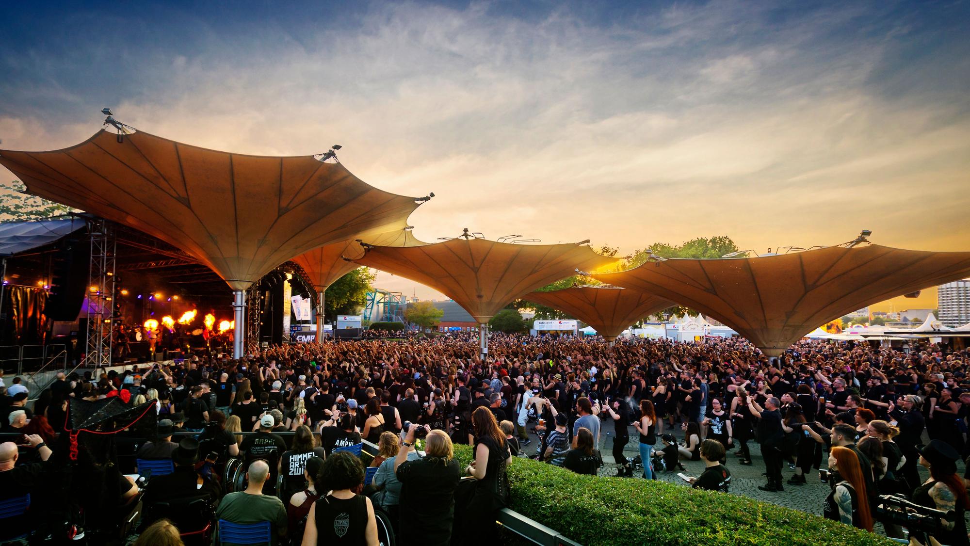 Besucher des Amphi Festivals stehen am Tanzbrunnen.