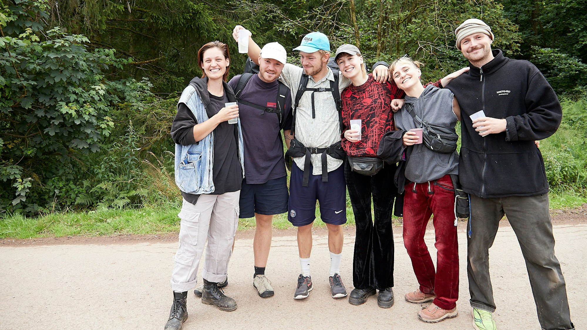 Sechs junge Leute stehen Arm in Arm auf einem Waldweg. Sie besuchen das Zugvögel-Festival am Weißen Stein in Hellenthal-Udenbreth.