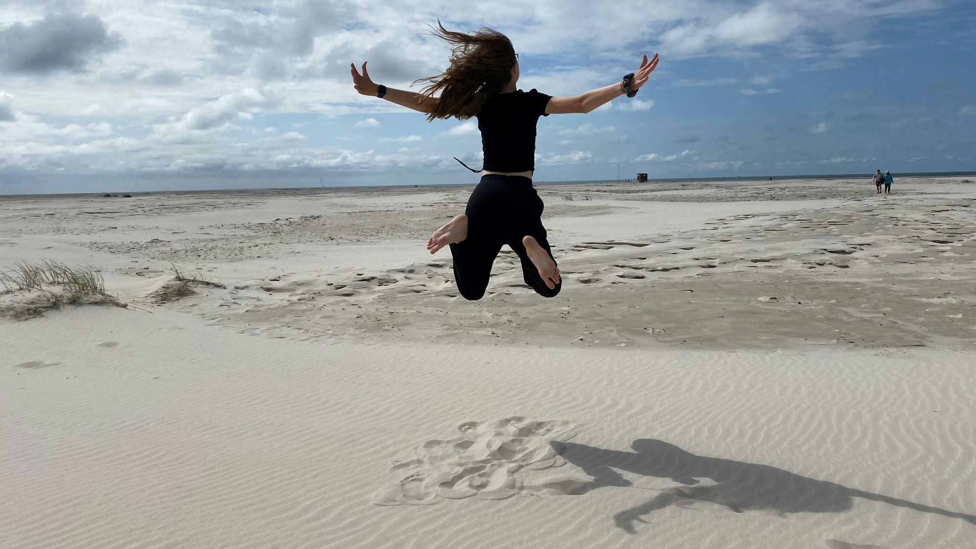 Das Bild zeigt ein Mädchen am Strand, das in die Luft springt.