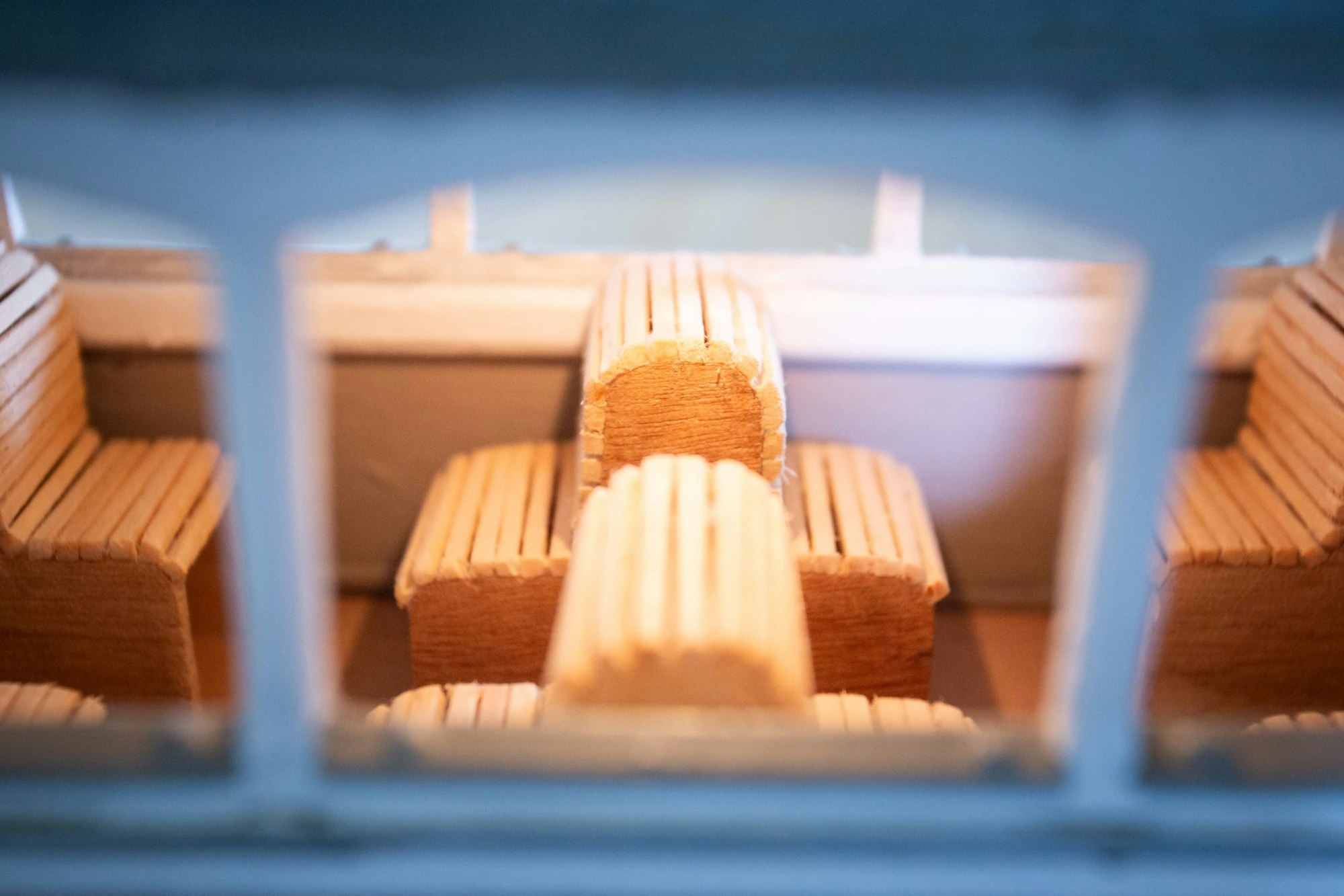 Detailaufnahme von Sitzbänken in einer Modellbahn, die Bänke sind aus Streichhölzern gemacht.