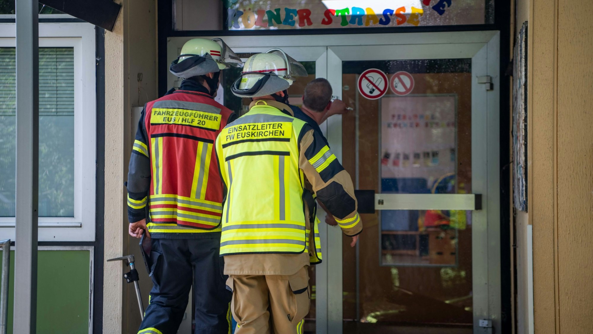 Das Bild zeigt, wie der Hausmeister den Feuerwehrmännern die Tür aufschließt.