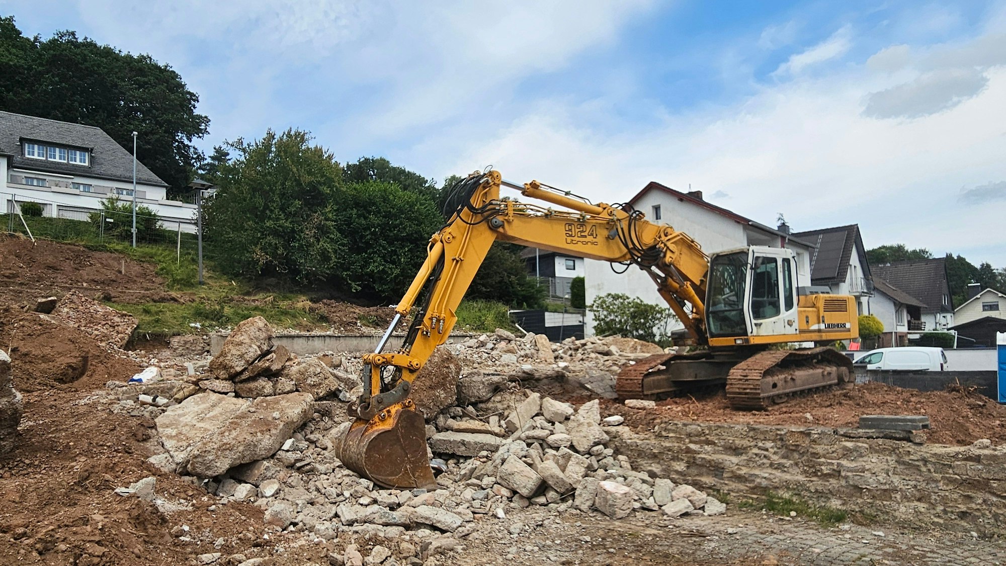 Ein Bagger steht auf den Resten des Hauses.