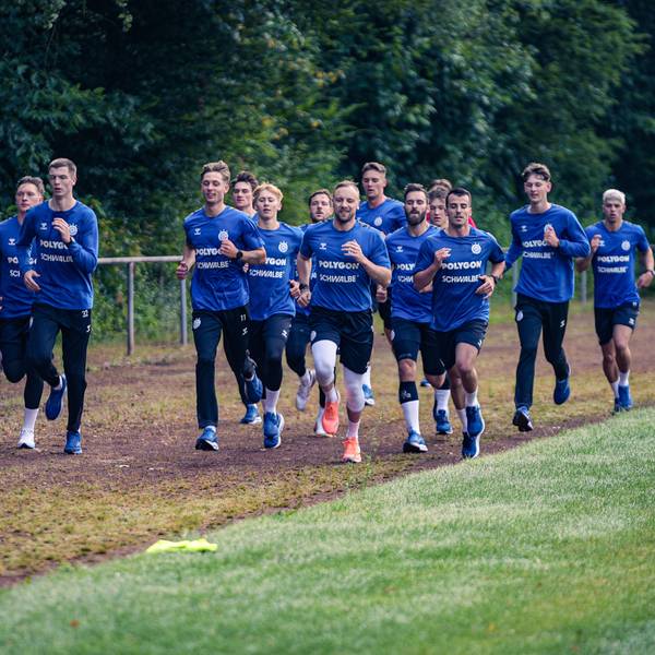 Zu sehen ist eine Handballmannschaft beim Laufen über das Trainingsgelände.