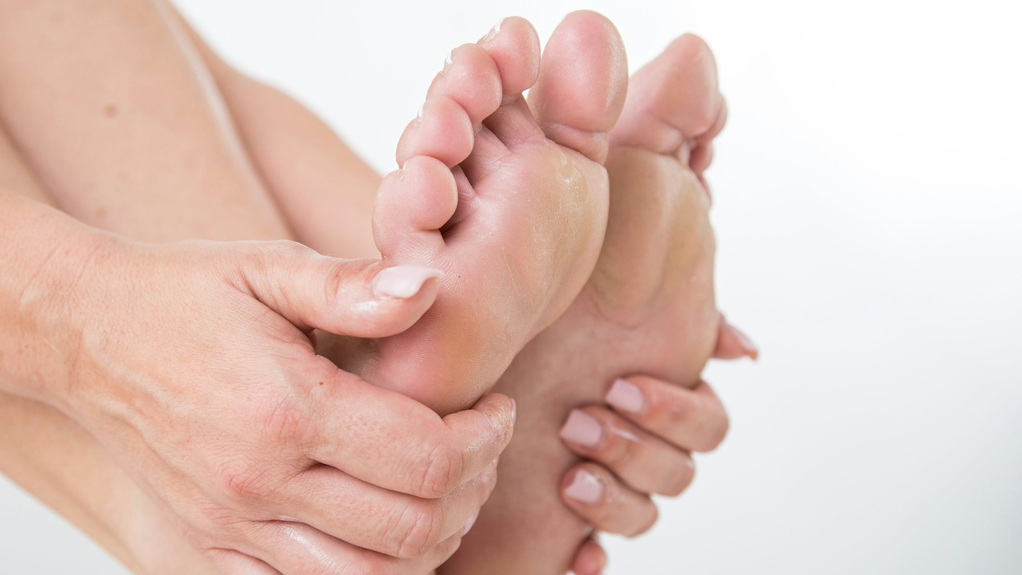 Zu sehen sind Füße, die von Händen umfasst werden.