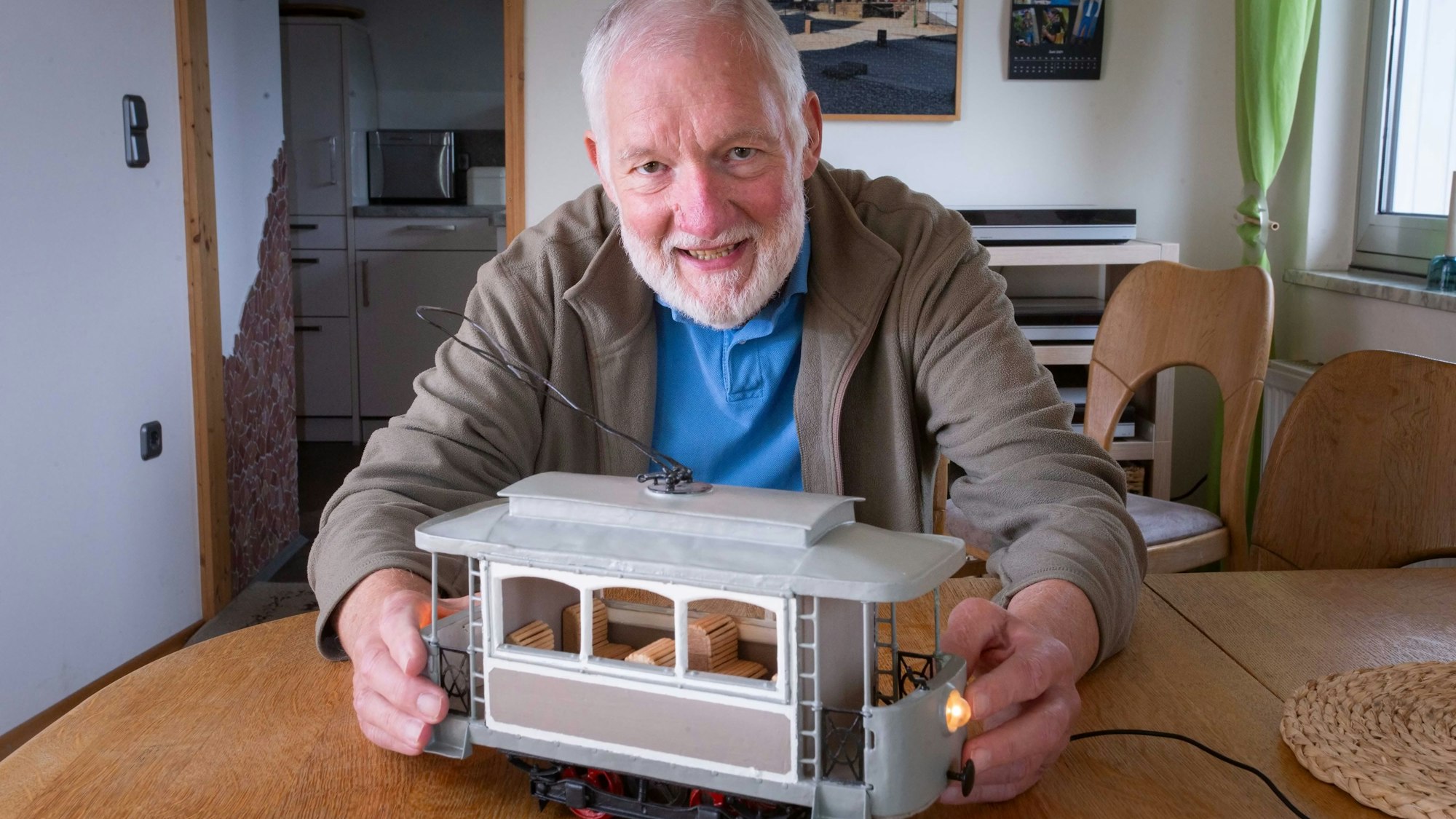Heinz Konietzka sitzt an einem Tisch, vor sich das Modell einer historischen Straßenbahn.
